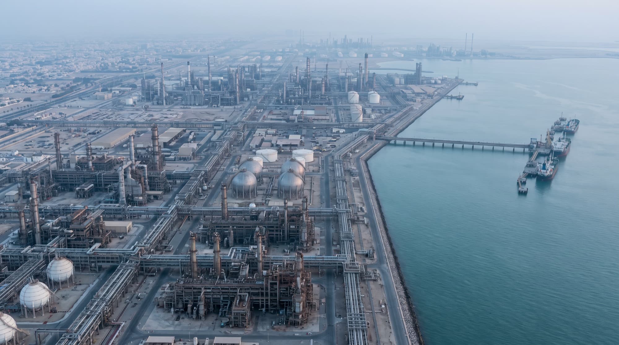 An aerial view of a coastal industrial city on the Arabian Gulf.